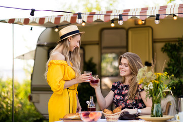 Friends at the table with fruit and pastries pour juice, laugh, communicate. Life in your own house outside the city. Cottages for rent for your family holidays