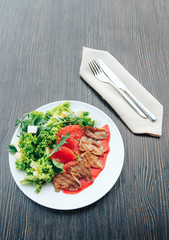 Salad of duck breast with grapefruit on a white plate. Background wooden table