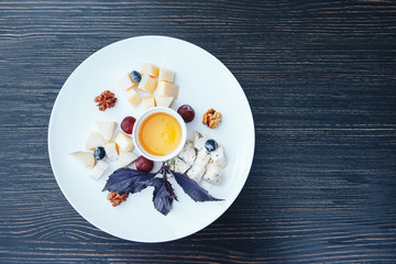 Cheese plate with nuts and honey. Cheese plate on a wooden table. top view