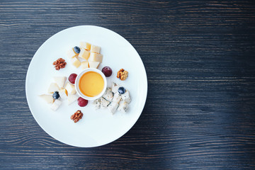 Cheese plate with nuts and honey. Cheese plate on a wooden table. top view