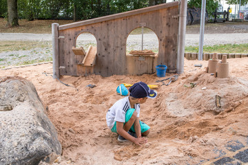 Junge mit Cap spielt in Sand in Sandkasten Spielplatz