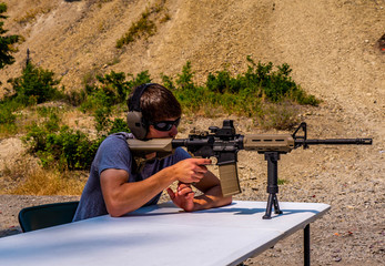 A young man concentrates as he fires his rifle at a paper target down range.
