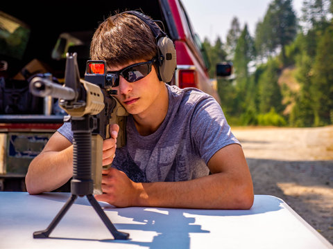 A young man concentrates as he fires his rifle at a paper target down range.