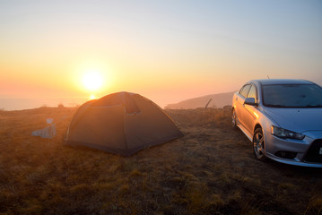 Dawn over the sea, Sunrise over the tent. Near the tent is a car.