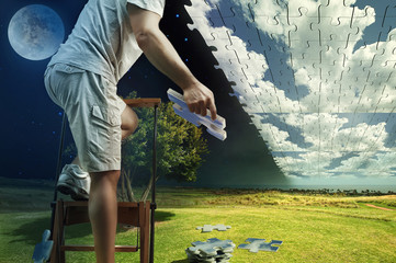 Man collects the sky from puzzles while standing on the ladder
