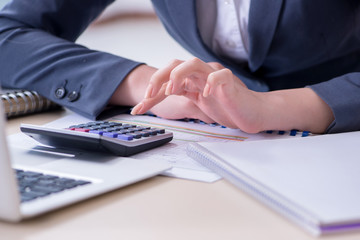 Female finance professional working on keyboard with reports