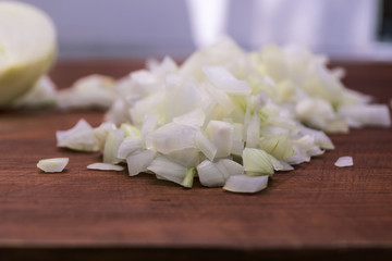 Obraz na płótnie Canvas Cut into small pieces white onions on a wooden background, close-up.