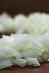 Sliced white onion close-up, vertical frame, wooden background.