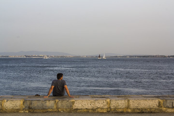 Men looking at the horizon in the river Tagus in a summer day