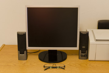 escritorio con monitor parlantes y gafas
