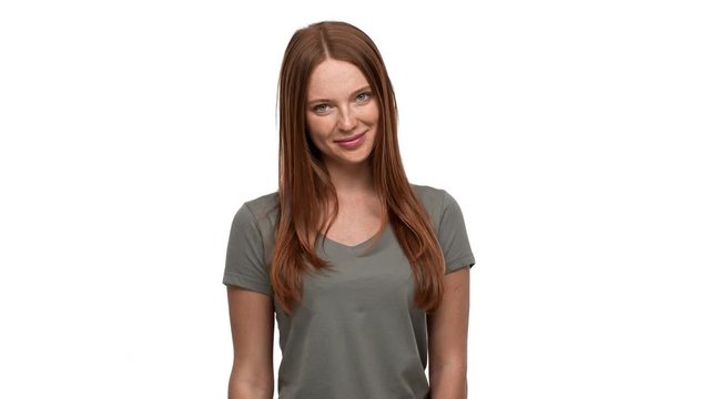 Portrait of pretty redhead woman 20s smiling and greeting person with waving hand, isolated over white background. Concept of emotions