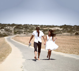 Couple kissing hugging walking on a road together hold hands. Romantic vacation, honeymoon love story