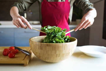 Young woman preparing salad in the kitchen.