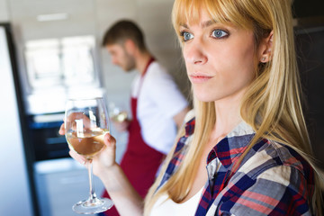 Serious young couple drinking wine in the kitchen at home.