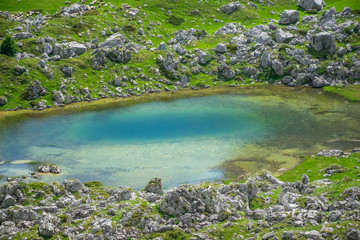 Naklejka na ściany i meble A small mountain lake among the high picturesque mountains.