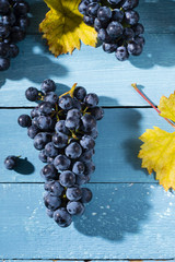 bunch of red grape with yellow leaf on old blue wood table background