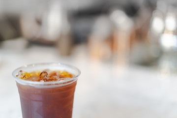 iced americano coffee on white table and blurred cafe as background
