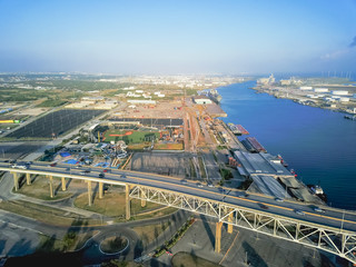 Aerial view of Corpus Christi Harbor Bridge with row of oil tanks and wind turbines farm in distance. A through arch bridge crosses the Corpus Christi Ship Channel © trongnguyen