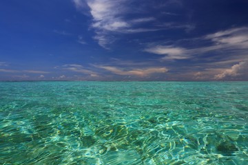 Colorful view of turquoise water of Indian Ocean surface and blue sky. Beautiful background. Maldives.