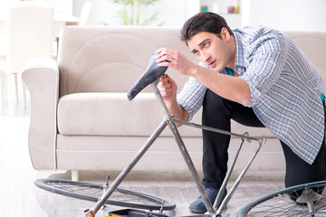 Young man repairing bicycle at home