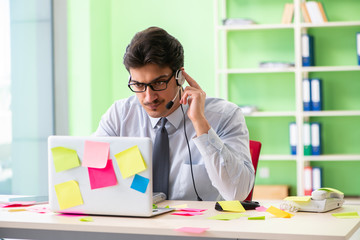 Young help desk operator working in office with many conflicting