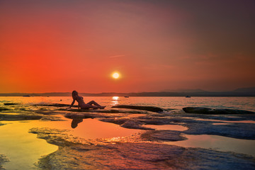 Beautiful woman admiring the sunset in Sirmione, Garda Lake