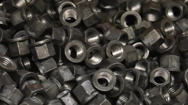 Production of steel screws in the factory ferrous metals. Hot red and orange nuts fall from the top to the container. Closeup