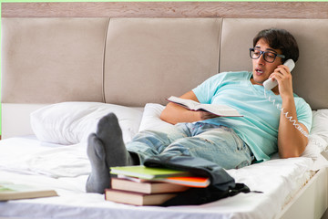Student preparing for exams at home in bedroom lying on the bed