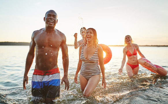 Laughing young friends wearing swimsuits having fun in a lake