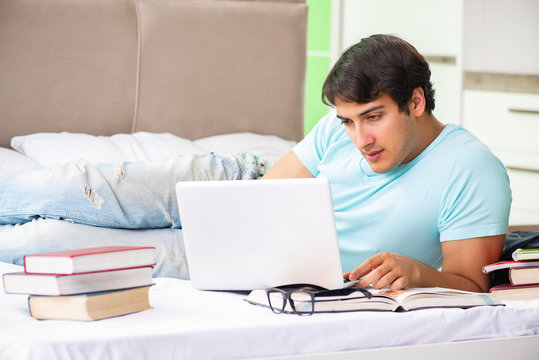 Student preparing for exams at home in bedroom lying on the bed