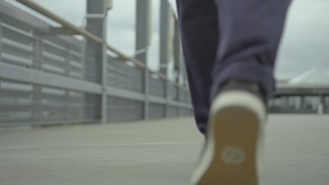 Young Girl walking away from the camera in a grey, concrete environment in slow motion