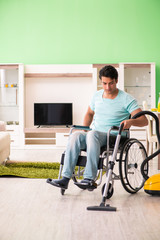 Fototapeta na wymiar Disabled man on wheelchair vacuum cleaning house