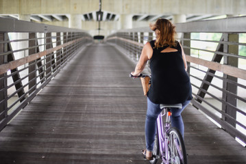 woman riding bike on bridge under highway in city