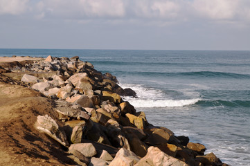 The rocky coastline on a beach of the Pacific Ocean in southern California, USA. Waves breaking up on the rocks on a sunny day in summer