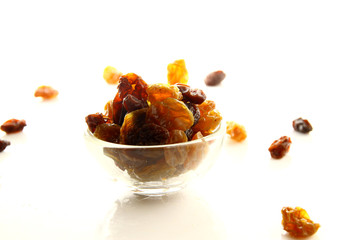 Raisins on white background / A raisin is a dried grape. Raisins are produced in many regions of the world and may be eaten raw or used in cooking, baking, and brewing