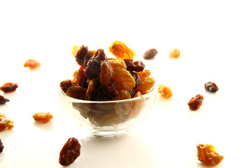Raisins on white background / A raisin is a dried grape. Raisins are produced in many regions of the world and may be eaten raw or used in cooking, baking, and brewing