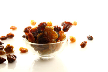 Raisins on white background / A raisin is a dried grape. Raisins are produced in many regions of the world and may be eaten raw or used in cooking, baking, and brewing