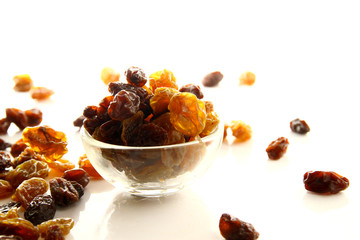 Raisins on white background / A raisin is a dried grape. Raisins are produced in many regions of the world and may be eaten raw or used in cooking, baking, and brewing