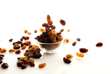 Raisins on white background / A raisin is a dried grape. Raisins are produced in many regions of the world and may be eaten raw or used in cooking, baking, and brewing