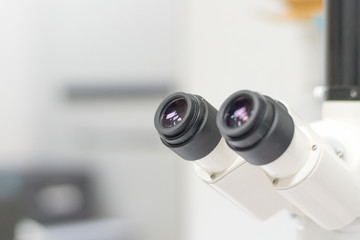 Selective focus of ocular eyepiece lenses and tube of binocular microscope for lab technician in laboratory research in hospital or university with white copyspace.Science Education Day