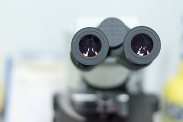 Selective focus of ocular eyepiece lenses and tube of binocular microscope for lab technician in laboratory research in hospital or university with white copyspace.Science Education Day