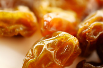 Close up raisin texture as background / A raisin is a dried grape. Raisins are produced in many regions of the world and may be eaten raw or used in cooking, baking, and brewing