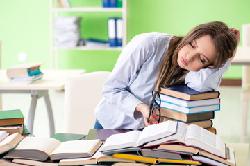 Young female student preparing for exams with many books 