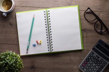 Office desk table blank notebook with smartphone, pencil,calculator,eye glasses