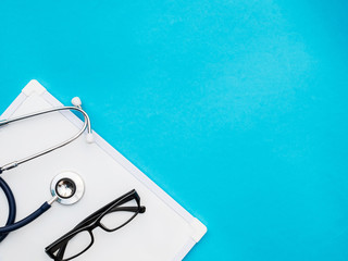 stethoscope with white board on blue background copy space