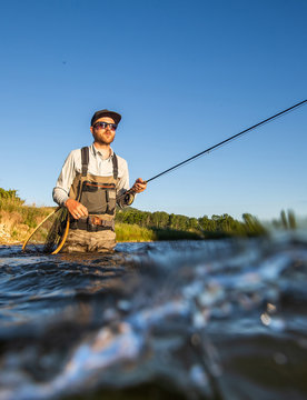 Over underwater shot of a man fly fishing in the summer in a river
