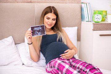 Happy young pregnant woman in the bed