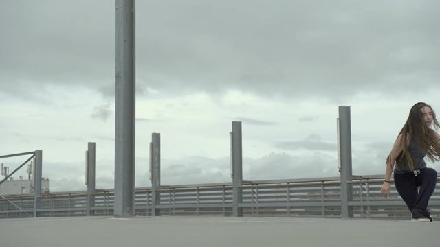 Young Girl performing urban dance style on a grey environment on a cloudy and windy day