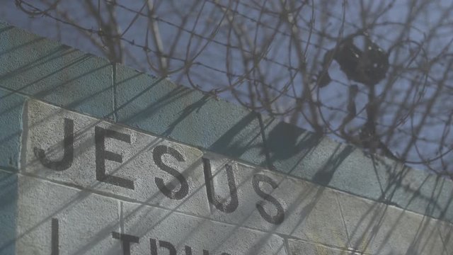 Cinderblock wall with Jesus written on it.