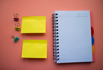 Сolorful blank sticky note or empty post notes with office clamps and notebook on orange background